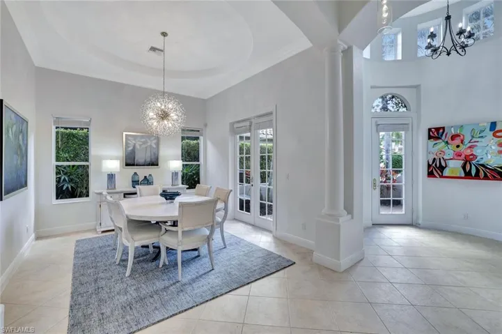 Dining room with a chandelier, a towering ceiling, crown molding, a tray ceiling, and light tile patterned floors