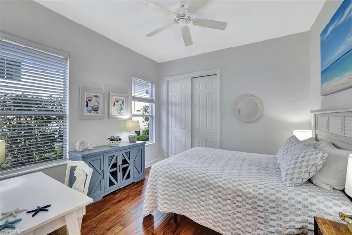 Bedroom with dark wood-style floors, a closet, and a ceiling fan