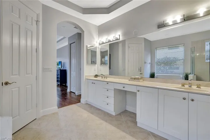 Bathroom featuring double vanity, light tile patterned flooring, and a tile shower