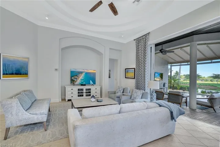 Living room with a ceiling fan, crown molding, and light tile patterned floors