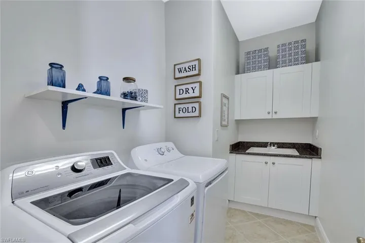 Washroom with washing machine and clothes dryer, light tile patterned floors, and cabinet space