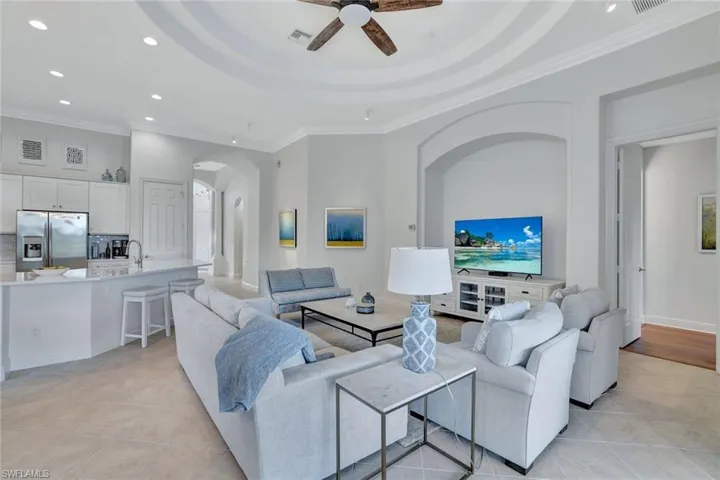 Living area featuring recessed lighting, ornamental molding, light tile patterned flooring, arched walkways, and ceiling fan