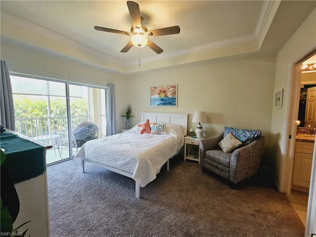 Large master bedroom with tray ceiling and a palm tree view