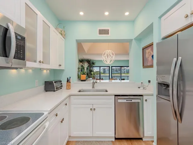 Kitchen with stainless steel appliances, white cabinetry, light wood-style floors, a eat in area with chandelier