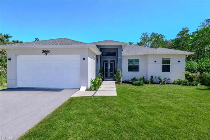Contemporary stucco exterior featuring a two-car garage, partial stone facade, and a flat concrete walkway
