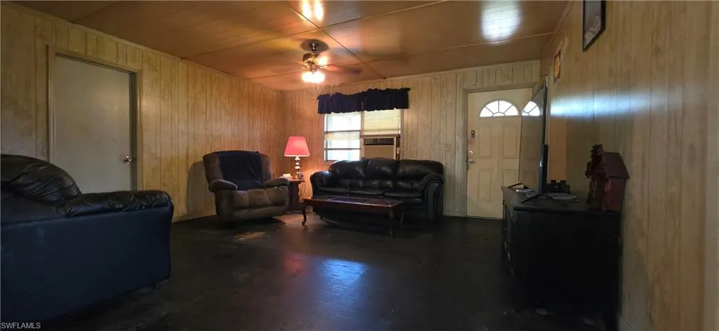 Interior room featuring light-toned wood paneling walls and a dark concrete floor
