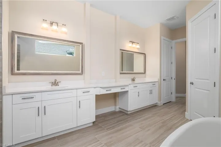 Bathroom featuring tile flooring, dual vanity, and a tub
