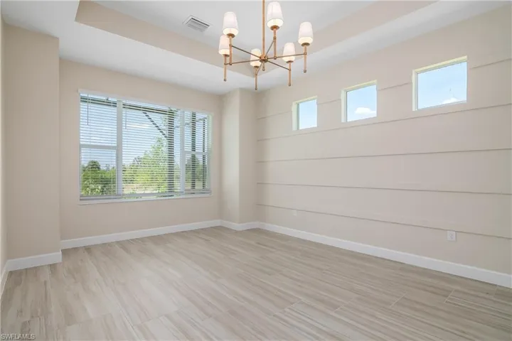 Empty room with a raised ceiling and an inviting chandelier
