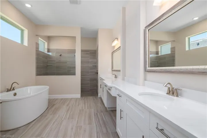 Bathroom featuring a healthy amount of sunlight, tiled shower, dual vanity, and tile flooring