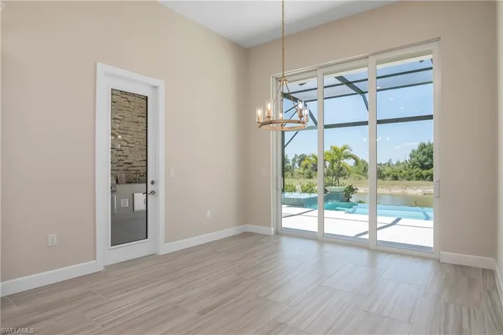 Empty room featuring a healthy amount of sunlight, a notable chandelier, and light tile floors