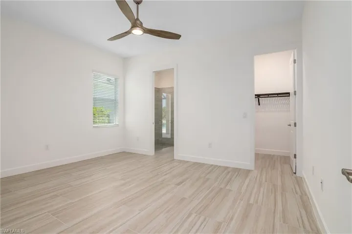 Unfurnished bedroom with ceiling fan, a closet, a walk in closet, and light tile floors