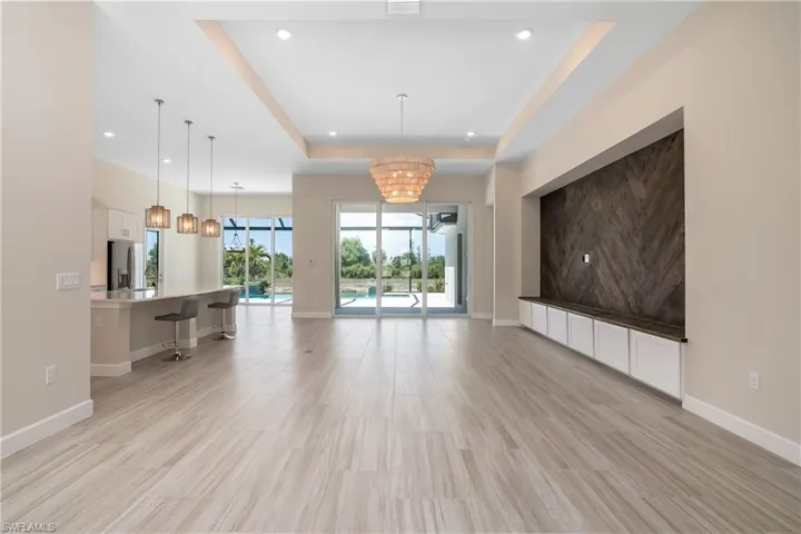 Unfurnished living room with a notable chandelier, a tray ceiling, and light tile floors