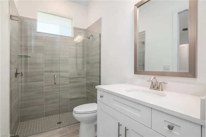 Bathroom featuring an enclosed shower, vanity, and toilet