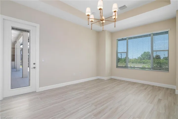 Tiled spare room featuring a notable chandelier and a raised ceiling
