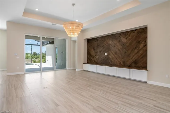 Tiled spare room featuring an inviting chandelier and a raised ceiling