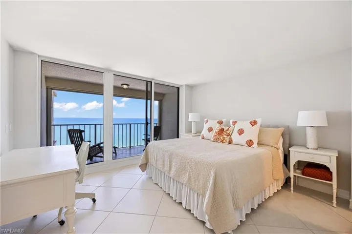 Bedroom with floor to ceiling windows, access to exterior, tile patterned floors, and a water view