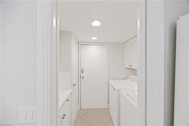 Washroom featuring light tile patterned flooring, cabinet space, washer and clothes dryer, and recessed lighting
