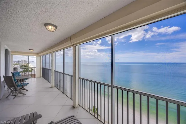 Sunroom featuring a balcony, a textured ceiling, a water view, and tile patterned floors
