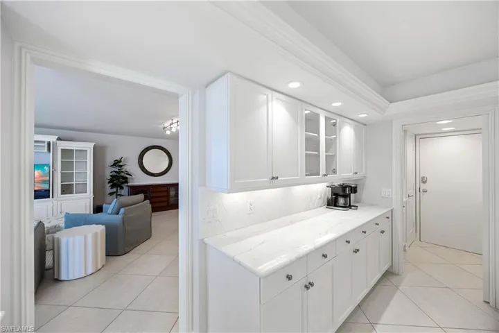 Kitchen with glass insert cabinets, light tile patterned floors, white cabinetry, light stone countertops, and recessed lighting