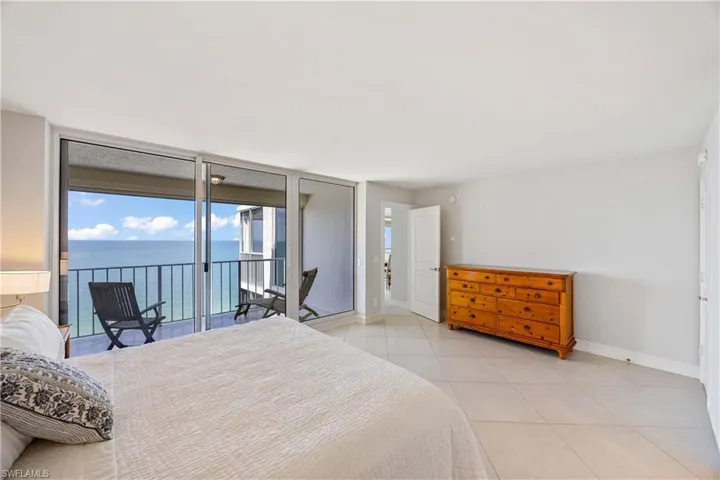 Bedroom featuring floor to ceiling windows, a water view, light tile patterned floors, and access to outside