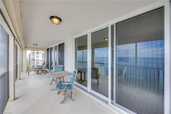 Sunroom / solarium with expansive windows, a textured ceiling, tile patterned flooring, a water view, and a balcony