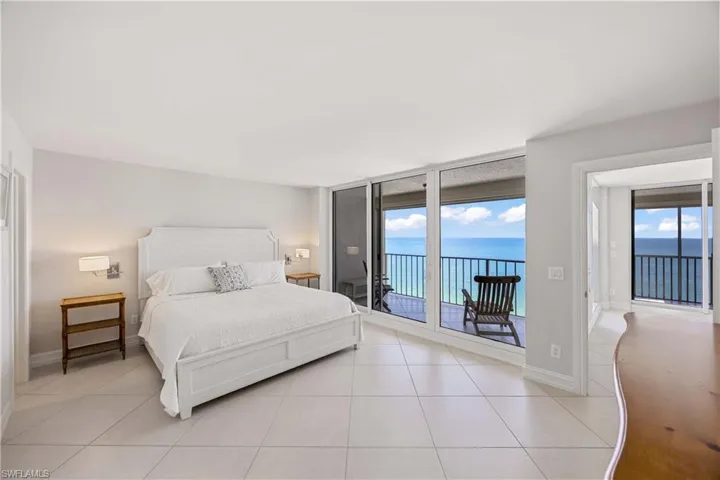 Bedroom with access to outside, a water view, expansive windows, and light tile patterned floors