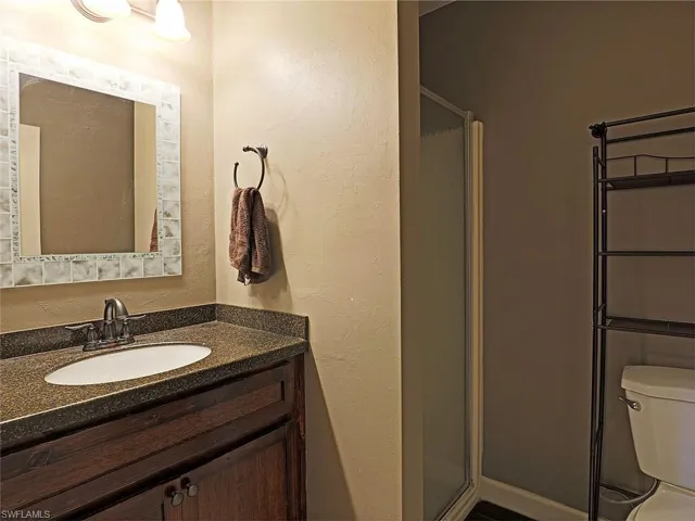 Bathroom featuring a dark wood-finish vanity with a built-in sink, stone-finish countertop, and a tiled mirror frame