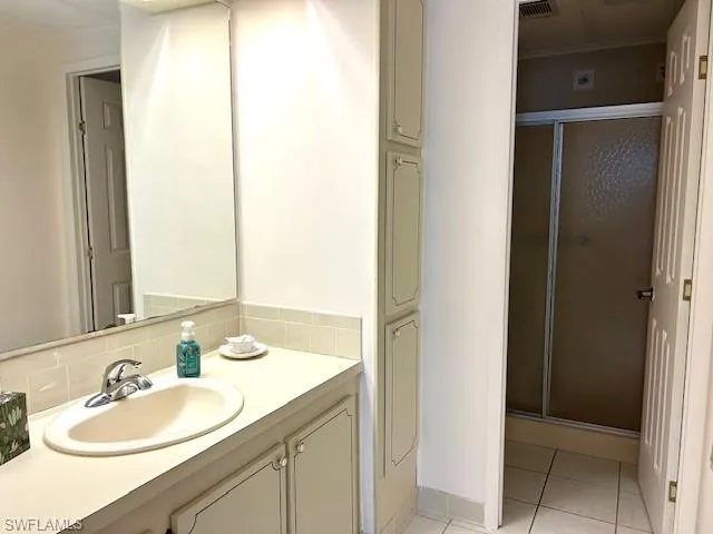 Full bath featuring a shower stall, vanity, and light tile patterned floors