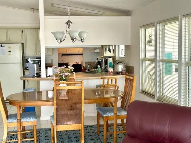 Kitchen with freestanding refrigerator, pendant lighting, light countertops, light tile patterned flooring, and a chandelier