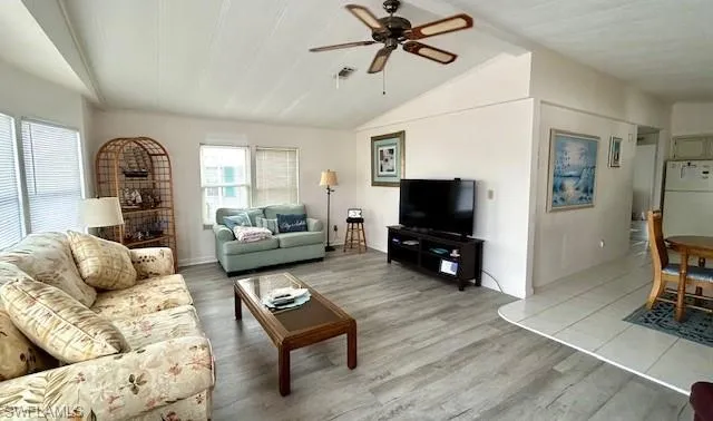 Living room featuring light wood finished floors, ceiling fan, and lofted ceiling