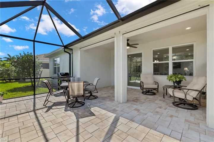 View of patio featuring a ceiling fan, glass enclosure, and outdoor dining space