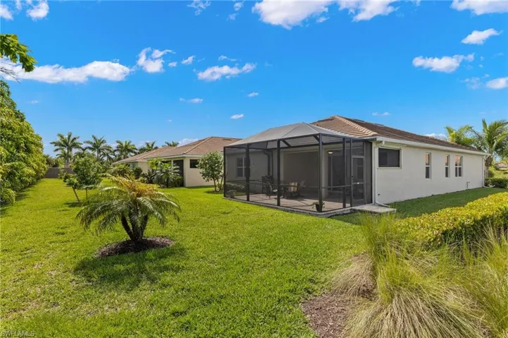 Rear view of property with a patio area, a lanai, a yard, and stucco siding