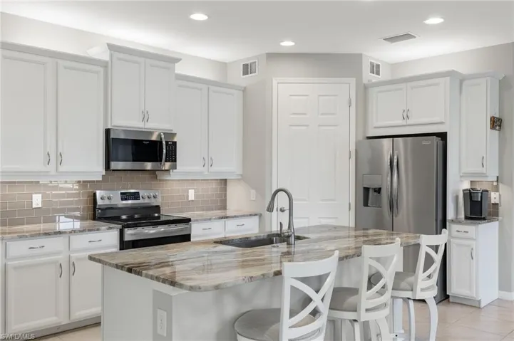 Kitchen with stainless steel appliances, visible vents, and a sink