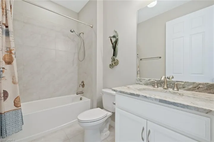 Bathroom with vanity, toilet, shower / tub combo with curtain, and tile patterned floors