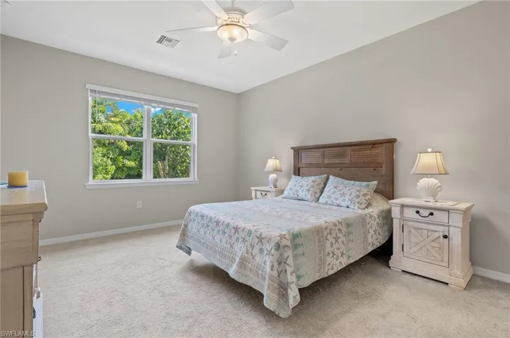 Bedroom featuring ceiling fan, light carpet, visible vents, and baseboards