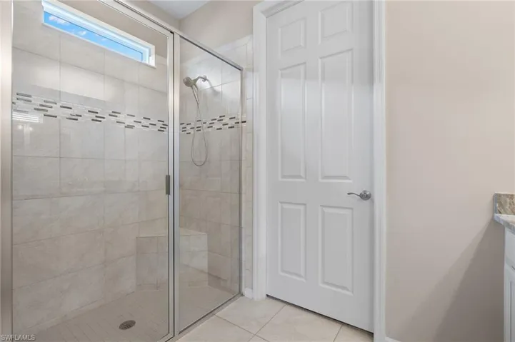 Full bath with baseboards, tile patterned flooring, and a stall shower