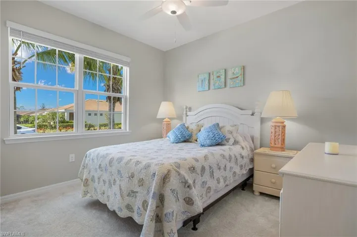 Bedroom with light carpet, a ceiling fan, and baseboards