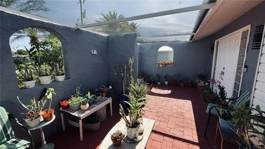 Enclosed patio with red brick pavers, a clear panel roof, and arched wall openings