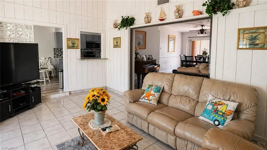 Spacious living area featuring white vertical paneling and light-toned tile flooring