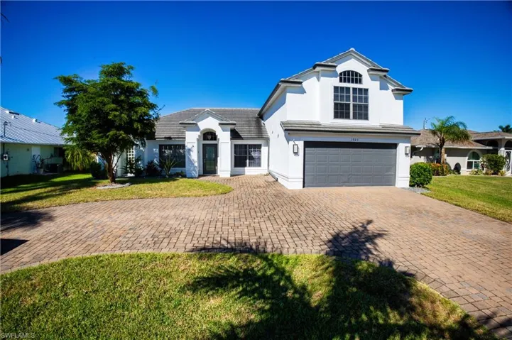 View of front of house featuring stucco siding, an attached garage, decorative driveway, and a front lawn
