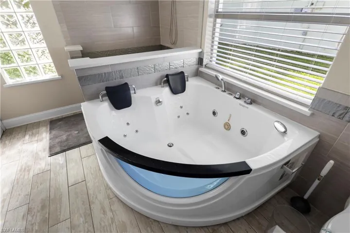 Full bath featuring a jetted tub and light wood finished floors