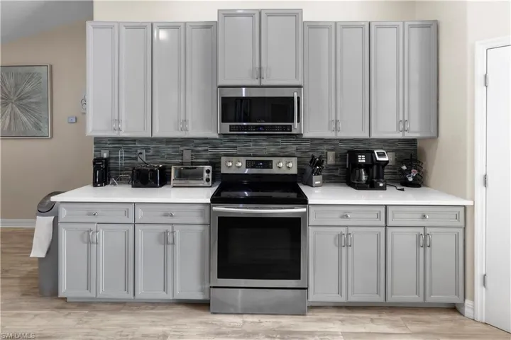 Kitchen with gray cabinets, appliances with stainless steel finishes, and tasteful backsplash