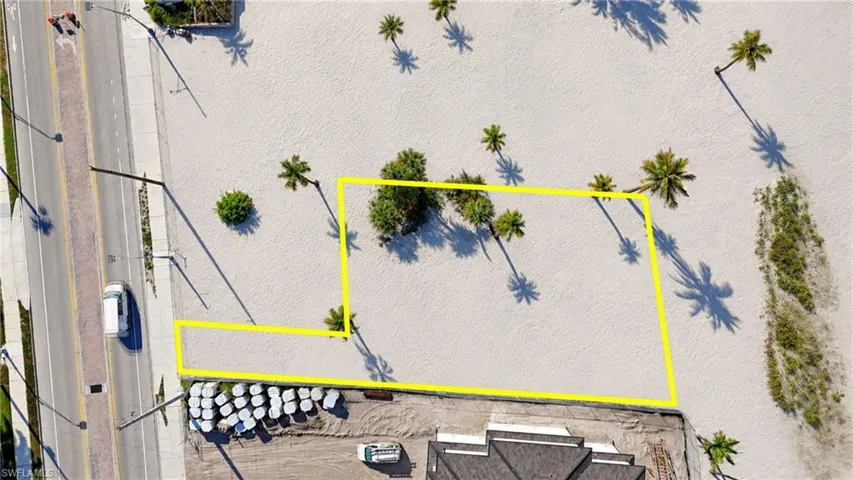 Expansive land parcel with direct road frontage, multiple palm trees, and sandy terrain - Virtually Edited Image