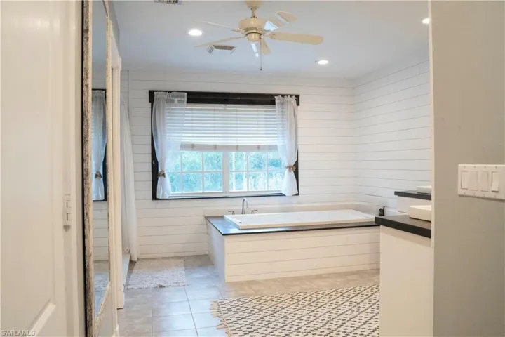 Jetted tub with decorative ship lap walls and double vanities with low profile vessel sinks.