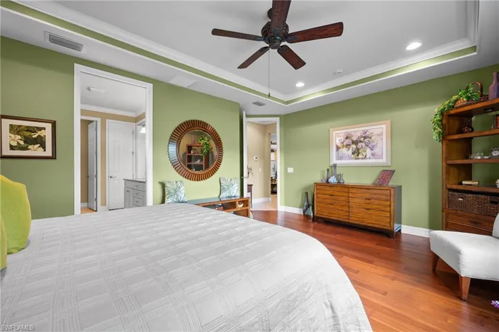 Tray ceiling with crown molding and recessed lighting, wood-finish flooring, and ceiling fan