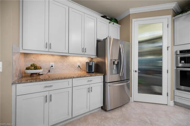 Kitchen featuring white shaker cabinetry, granite countertops, and stainless steel appliances