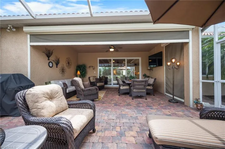 Screened patio featuring a multi-tone paver floor, textured stucco walls, and a ceiling fan