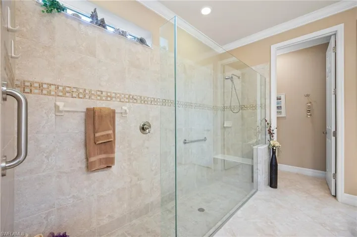 Walk-in shower with clear glass enclosure and light-toned tilework