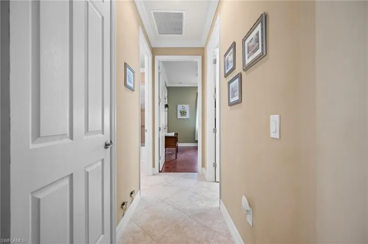 Hallway featuring light beige wall paint, white trim, and light-toned diamond-patterned tile flooring