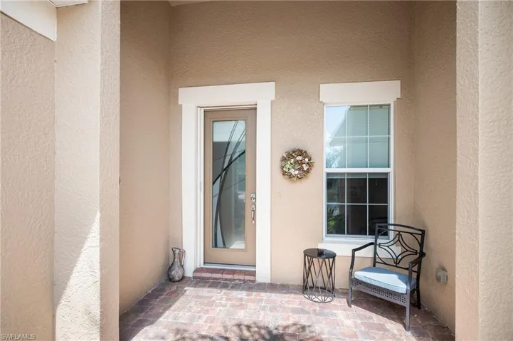Entryway featuring a full-light door with decorative glass, a prominent window with grid inserts, and brick paver flooring